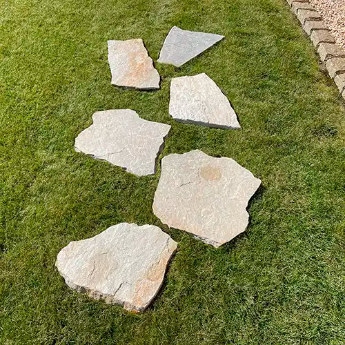 Parallel versetzt verlegte Clara Quarzit Trittplatten auf dem Rasen