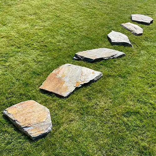 Grauwacke Trittplatten linear frei verlegt auf der Grasfläche