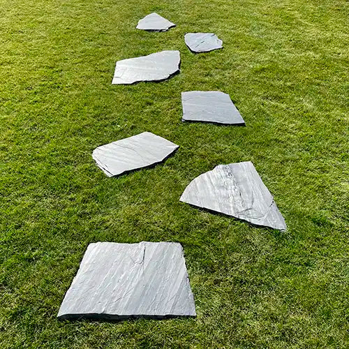 Schiefer Negra Trittplatten. Parallel versetzt verlegt auf der Wiese.