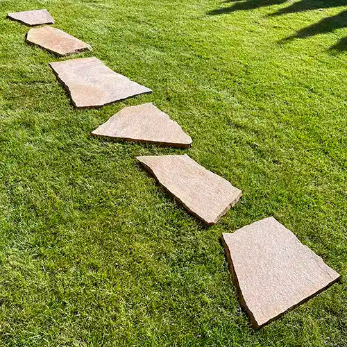 Lineare Verlegung von Porphyr Trittplatten auf der Wiese