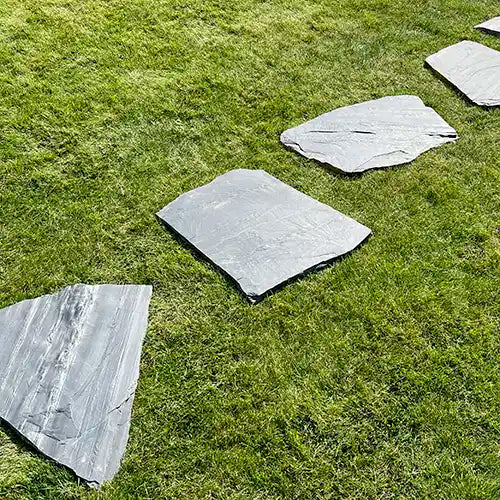 Lineare Verlegung von Trittplatten Schiefer Negra auf dem Rasen
