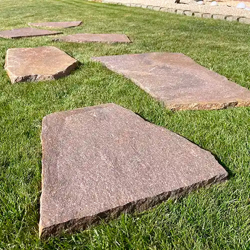 Paralell versetzte Porphyr Trittplatten auf der Wiese. Lose gelegt.