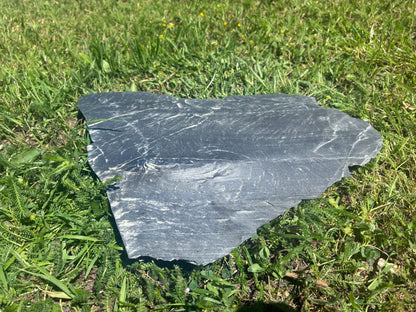 Polygonale Schiefer Negra Trittplatten aus Naturstein als stilvoller Gartenweg im Rasen mit anthrazitfarbener Schieferoberfläche.