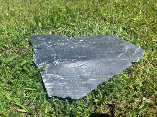 Polygonale Schiefer Negra Trittplatten aus Naturstein als stilvoller Gartenweg im Rasen mit anthrazitfarbener Schieferoberfläche.