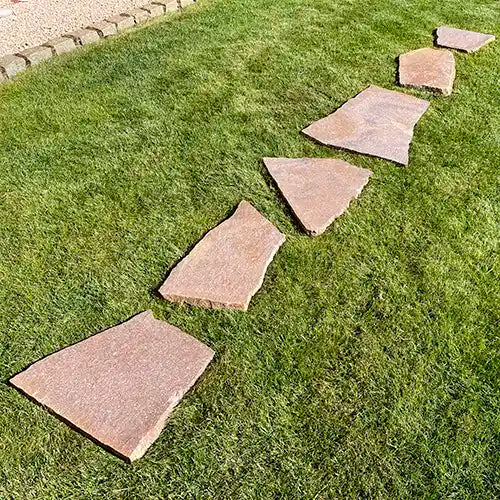 Porphyr Trittplatten linear frei verlegt auf der Grasfläche